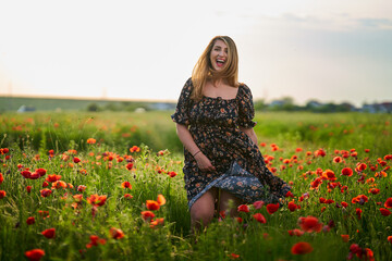 Beautiful plus size woman in a poppy field - obrazy, fototapety, plakaty