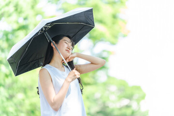 日傘をさすアジア人女性（体調不良・汗）
