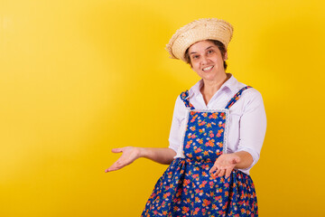 Mature woman dressed in typical Festa Junina clothes. With open arms, welcome.