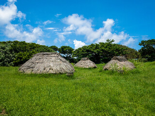晴れた日の沖縄県うるま市伊計島にある茅葺き屋根が再現された仲原遺跡