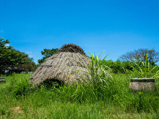 Fototapeta na wymiar 晴れた日の沖縄県うるま市伊計島にある茅葺き屋根が再現された仲原遺跡