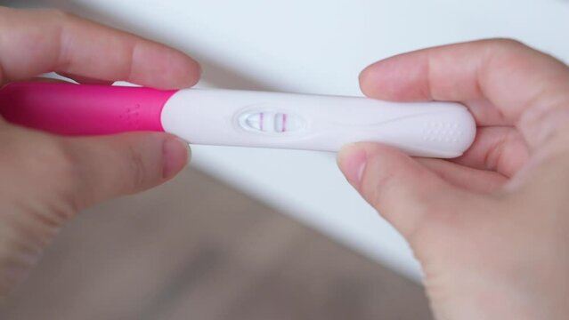 Female hands holding pregnancy test. Woman making test - result is positive, show two lines. Pregnancy concept, family planning.