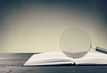 Magnifying glass and opened book on the desk, learning, research searching information concept
