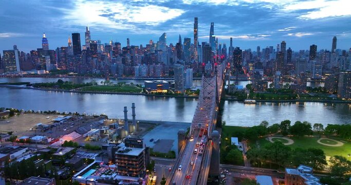Evening falling on the beautiful New York. Queensboro Bridge over the river. Never sleeping city switching on lights. Aerial view.