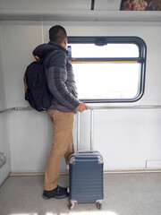 Latino adult man is transported on the light rail without a driver arriving in Vancouver Canada with a face mask due to the Covid-19 pandemic, he uses his cell phone to see maps and send messages
