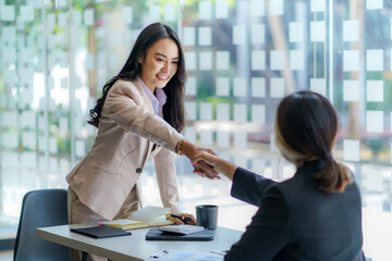 Happy young Asian business people shaking hands to congratulate success. Business executives handshake to congratulate the joint business agreement.