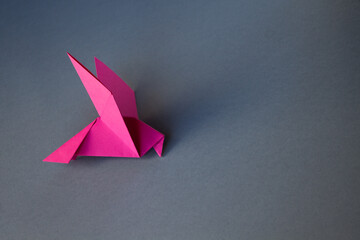 Pink paper dove origami isolated on a grey background