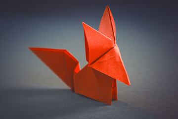 Orange paper fox origami isolated on a grey background