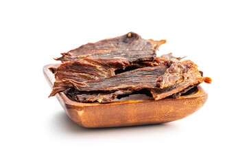 Beef jerky meat in wooden bowl. Dried sliced meat isolated on white background.