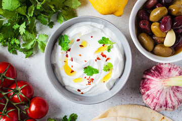 Whipped feta cheese dip with garlic and lemon in gray bowl, flat lay. Greek cuisine concept.
