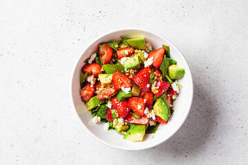 Strawberry, avocado and feta cheese salad with mustard dressing in white bowl. Summer recipe.