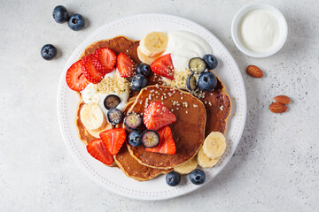 Summer breakfast. Pancakes with strawberries, blueberries, banana and cream on white plate. Vegan recipe.