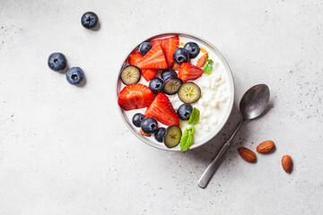 Cottage cheese with strawberries, nuts and blueberries in gray bowl for breakfast. Summer recipe.