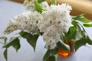 Bouquet of white lilacs in a yellow glass vase on the table
