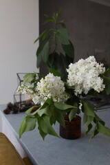 Bouquet of white lilacs in a yellow glass vase on the table