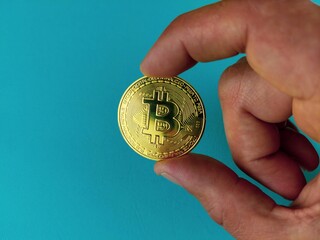 Bitcoin in hand. A physical bit coin. Digital currency. Cryptocurrency. A gold coin with a bitcoin symbol, on a hay background. Close-up. The concept of a virtual cryptocurrency.