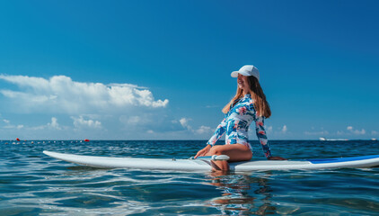 Healthy happy fit woman in bikini relaxing on a sup surfboard, floating on the clear turquoise sea water. Recreational Sports. Stand Up Paddle boarding. Summer fun, holidays travel. Active lifestyle