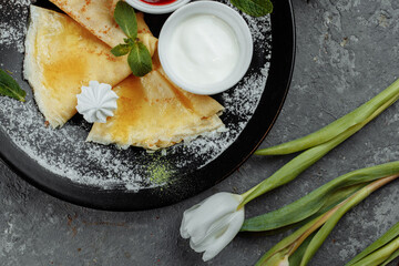 Pancakes with strawberries and creme black plate