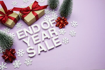 End of Year Sale alphabet letters with gift boxes, snowflake and artificial christmas tree on purple background
