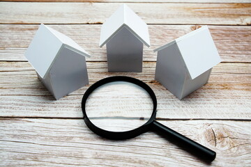 White Model House and magnifying glass with space copy on wooden background