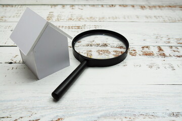 White Model House and magnifying glass with space copy on wooden background