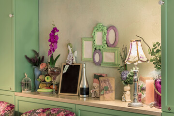Various Provence-style decor items on wooden shelf and photo frames on wall