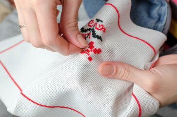 A woman embroiders the national symbols of Ukraine with a cross. Close-up of female hands...