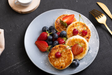 Roasted cheesecakes on a plate with powdered sugar and berries angle view