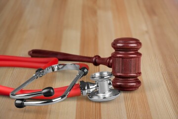 Judge gavel and medical stethoscope on wooden desk. Health and Law concept.