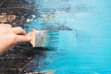 Close up paintbrush in hand and painting on the wooden table.