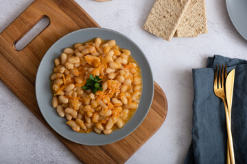 Stewed beans with vegetables in spicy tomato sauce on a plate top view.