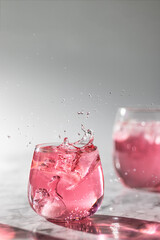 The glasses og pink drink with ice and splashes