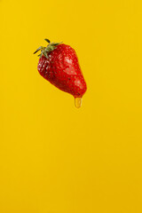 Strawberry with honey drips on it over yellow background