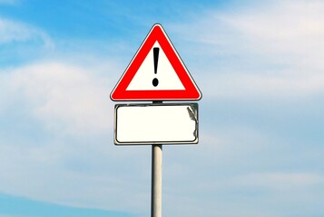 Warning triangular sign with exclamation mark.  Worn blank white signpost below blue and  cloudy sky. Background for copy space.