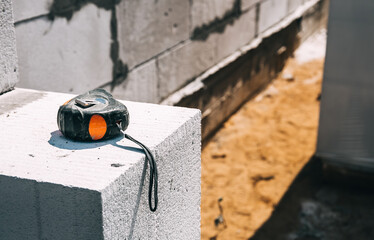 The tape measure lies on a gas silicate block close-up. Construction site. Copy space. The concept of technical supervision and measurement of completed construction stages of work. Building material