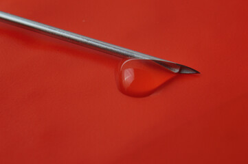 Syringe needle and a drop of a transparent substance. close-up