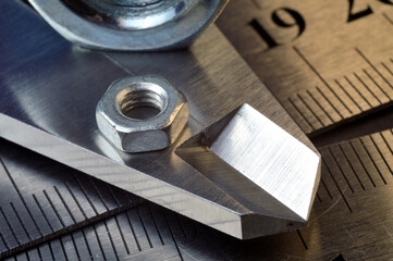 Accurate measuring tool caliper and metal ruler lie in place with nuts. close-up.