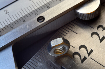 Accurate measuring tool caliper and metal ruler lie in place with nuts. close-up.