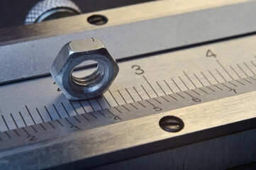 Accurate measuring tool caliper and metal ruler lie in place with nuts. close-up.