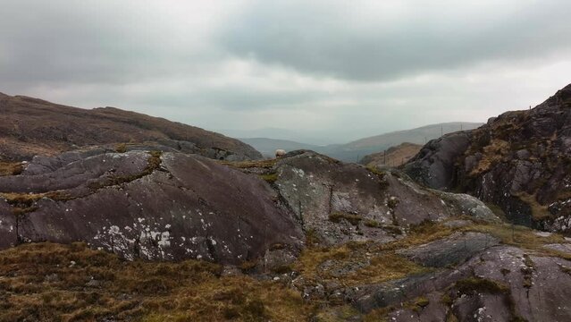 Molls Gap, Killarney, Kerry, Ireland, March 2022. Drone ascends and pushes south above Beaufort under a moody sky with views south towards Carhoomeengar with Kenmare in the distance.