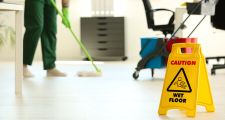WET FLOOR sign and janitor with mop in office