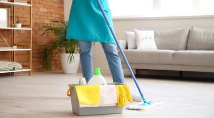 Young woman mopping floor in living room