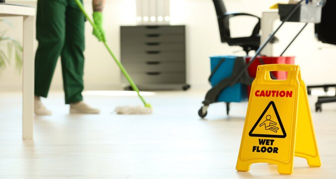 WET FLOOR Sign And Janitor With Mop In Office