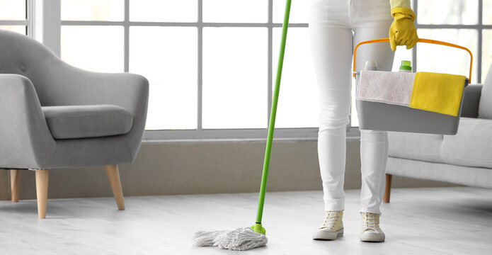 Young woman mopping floor in room