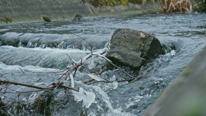 Crystals of Ice and Icicles Forming on Bank of Fast Flowing Clean Water Stream on Cold Day	