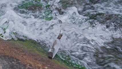 Crystals of Ice and Icicles Forming on Bank of Fast Flowing Clean Water Stream on Cold Day	