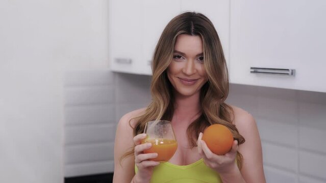 Happy dark blond woman with freshly squeezed orange juice and fruit in the hands. Eating proper food with vitamins. Vegetarian lifestyle