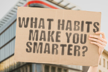 The question " What habits make you smarter? " is on a banner in men's hands with blurred background. Smart. Task. Wellness. Smarter. Productive. Effect. Habits. Use. Sad. Skill. Advice. Tip. Work