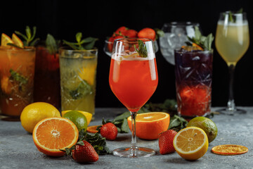 Colorful refreshing drinks for summer, cold strawberry lemonade juice with ice cubes in the glasses garnished with sliced fresh lemons