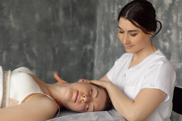 Osteopath in medical cabinet massage cervical vertebrae of woman lying down on hospital couch in...